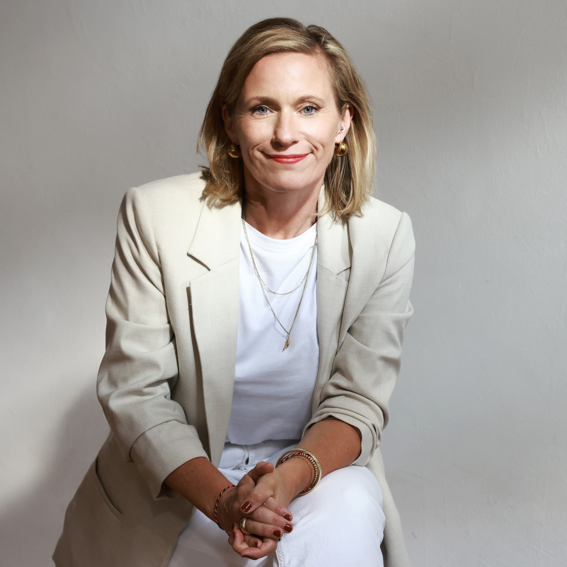 leadership_consulting_final Portrait von Charlotte sitzend in einem beigefarbenem Jacket und weißer Jeans.